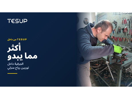 فني من TESUP يركّب دوّار المولّد وعموده على طاولة عمل أمام جدار من الأدوات، مع العنوان: أكثر مما يبدو، الحِرفية داخل توربين رياح منزلي