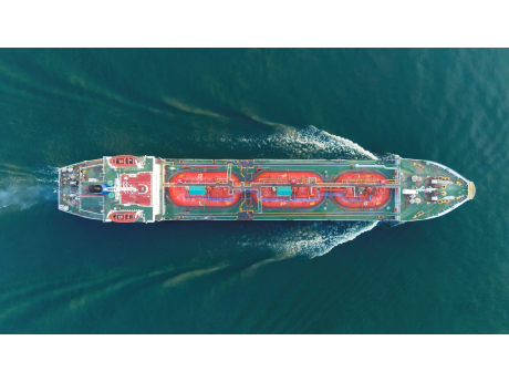A gas tanker under way on open sea, seen from above with its wake behind it