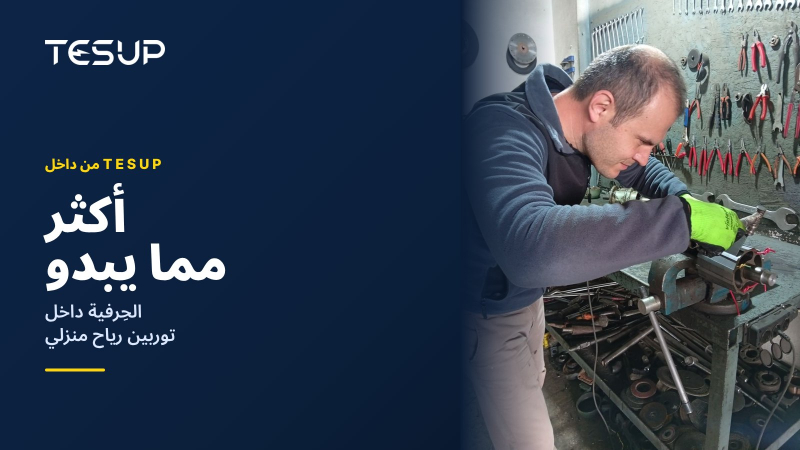 فني من TESUP يركّب دوّار المولّد وعموده على طاولة عمل أمام جدار من الأدوات، مع العنوان: أكثر مما يبدو، الحِرفية داخل توربين رياح منزلي