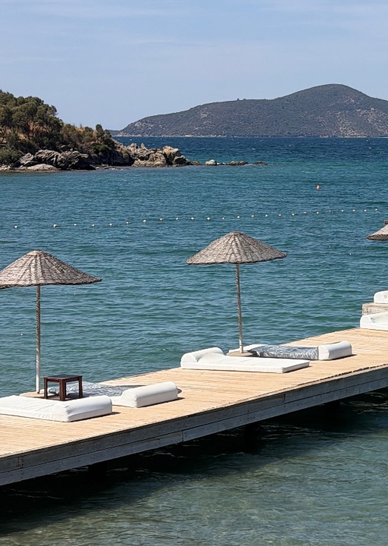 Med-Inn pier on Güllük Bay with sun loungers, straw parasols and calm blue water