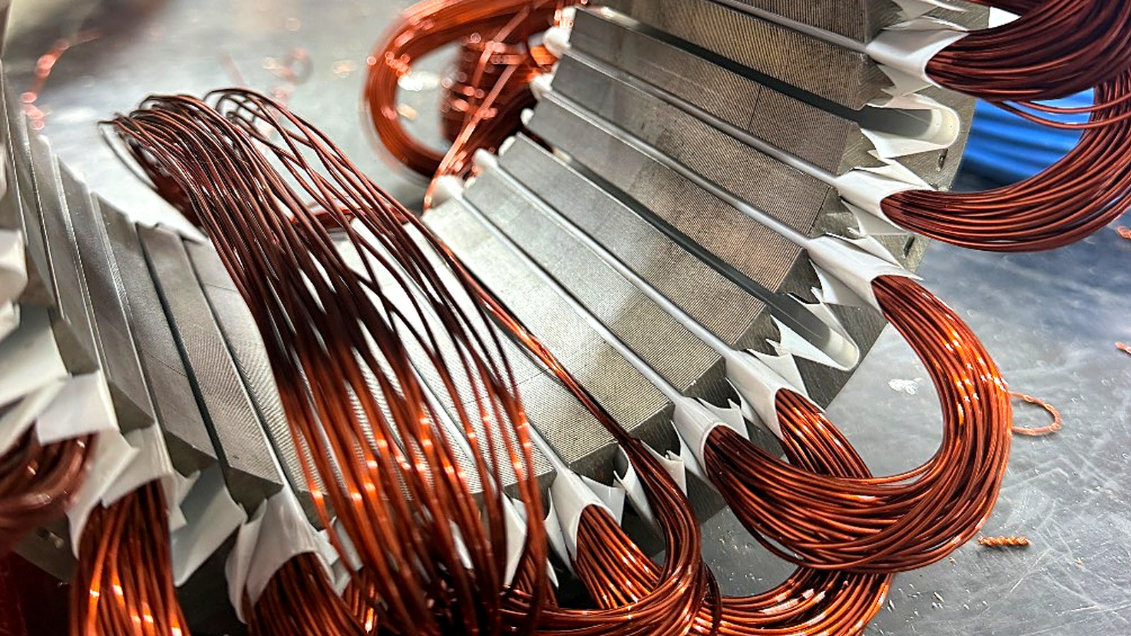 Nahaufnahme eines Stators: Elektrobleche, weiße Nutisolation und Schleifen aus 0,90 mm Kupferdraht