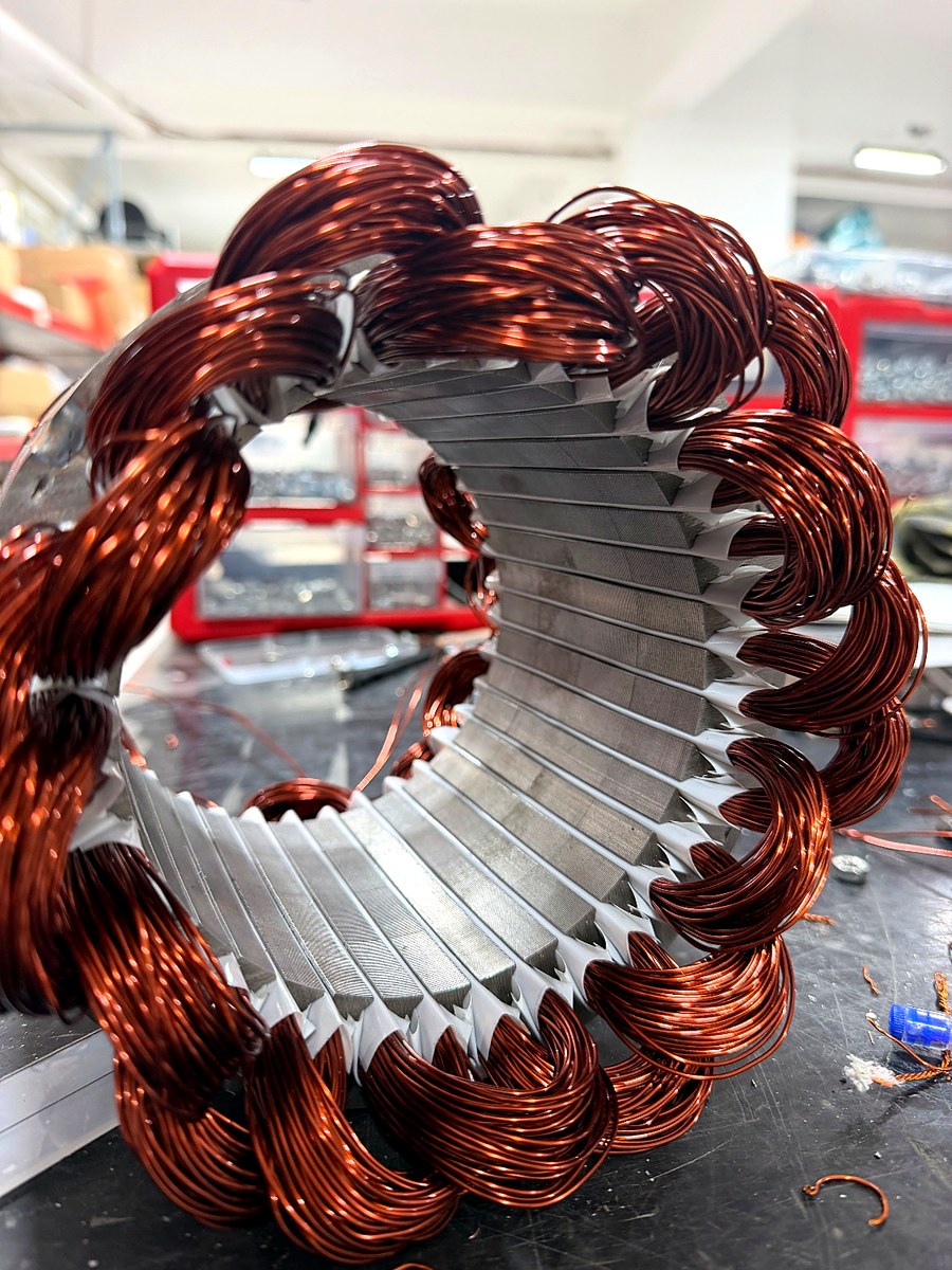 Ein fertig gewickelter TESUP Stator auf der Wickelbank, rundum mit Kupferspulen