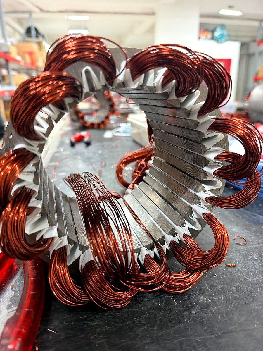 Ein gewickelter Stator im Vordergrund, dahinter ein weiterer Stator auf der Wickelbank