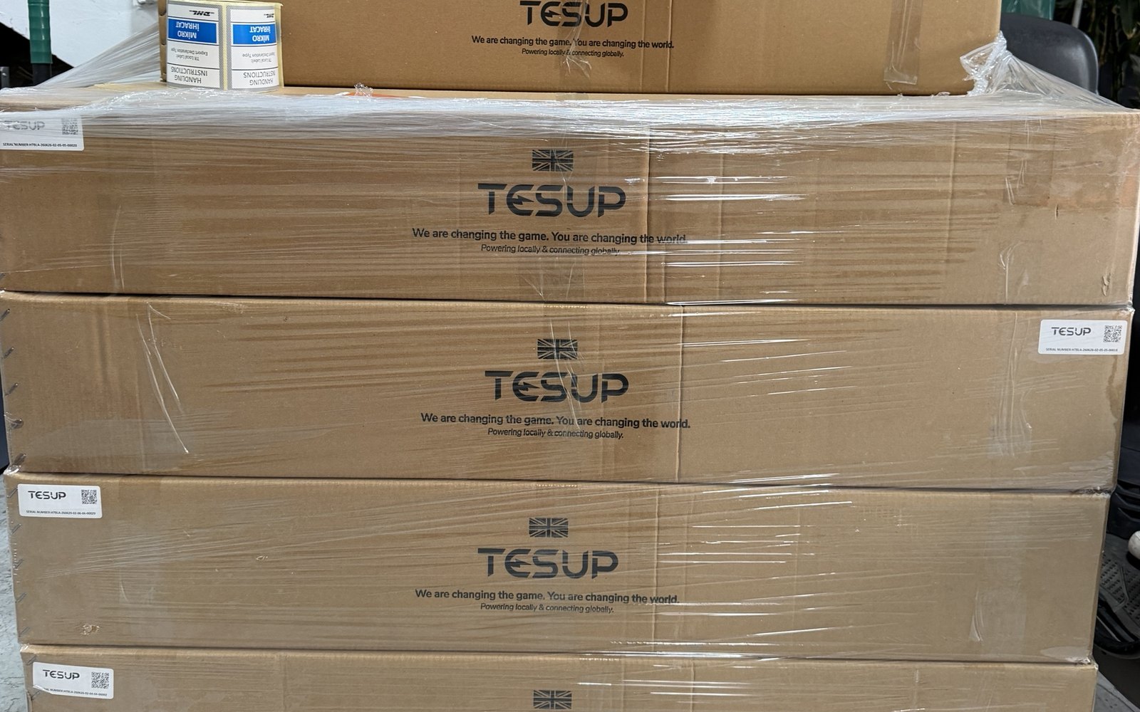 Stacked TESUP boxes wrapped on a pallet, each labelled with a serial number