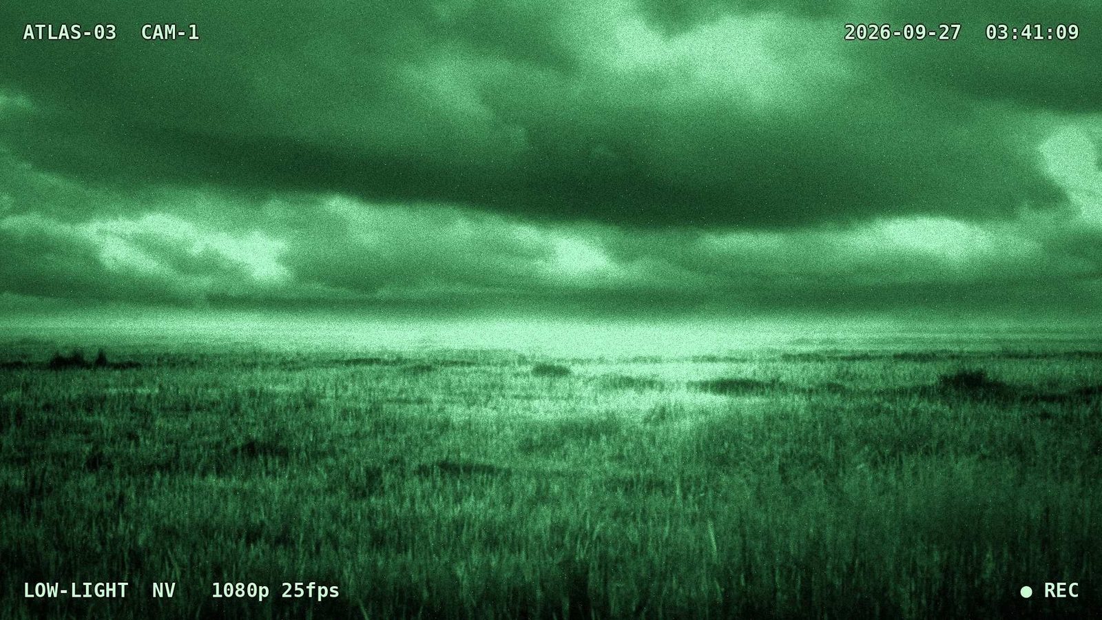 Imagen verde de visión nocturna de un pastizal bajo nubes densas