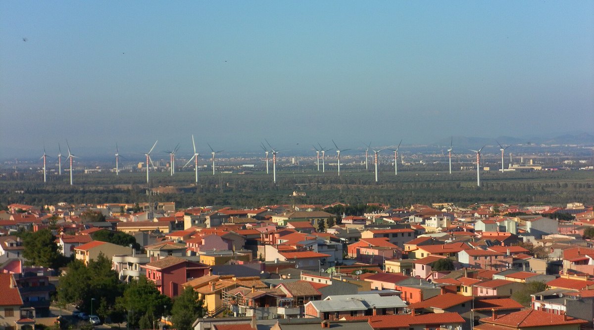 Cagliari yakınlarında, Capoterra'nın çatılarının ötesindeki ovada duran rüzgâr türbinleri