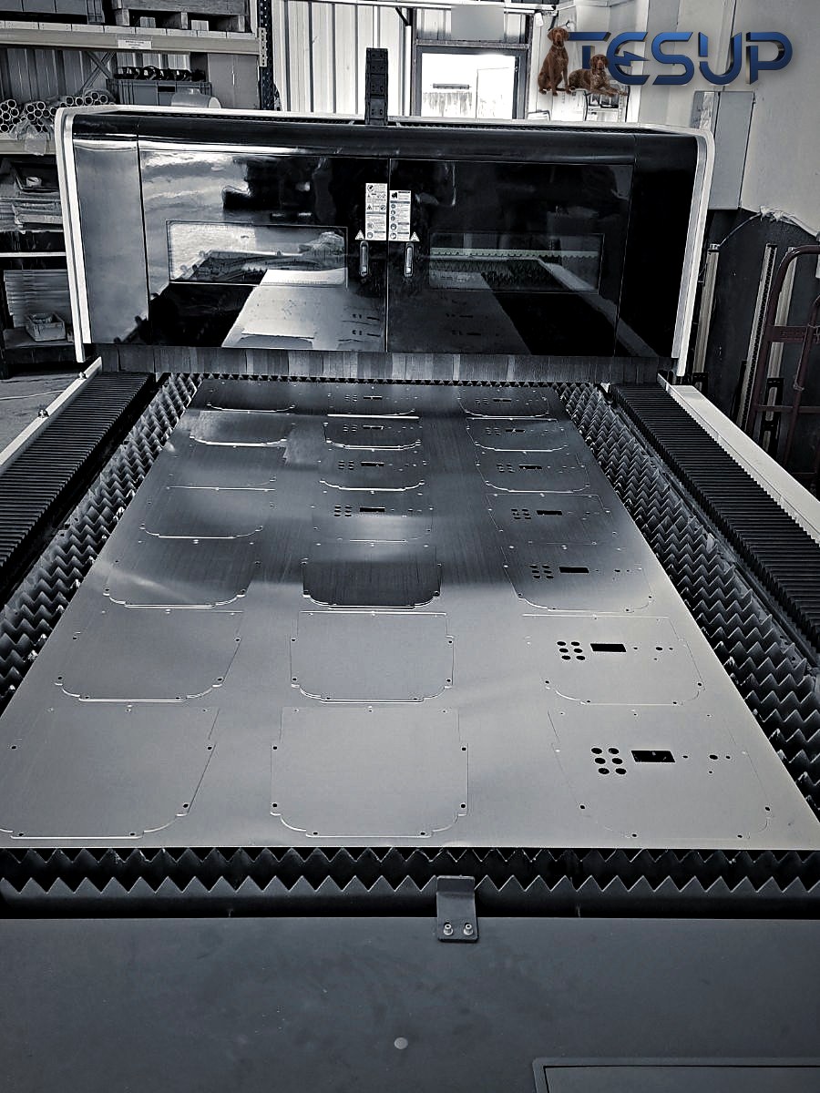 A fibre laser cutting bed with an aluminium sheet full of precisely cut parts