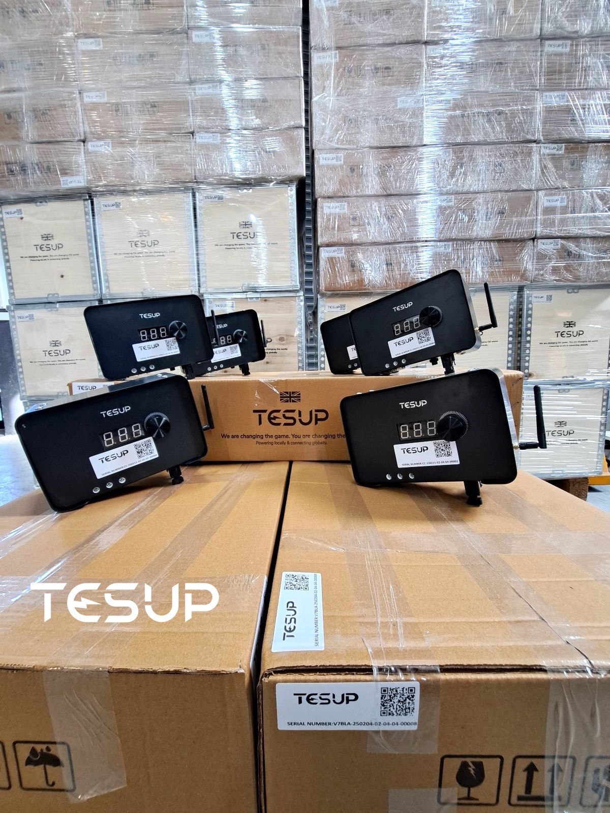TESUP charge controllers lined up on TESUP cartons in front of a wall of wrapped TESUP boxes