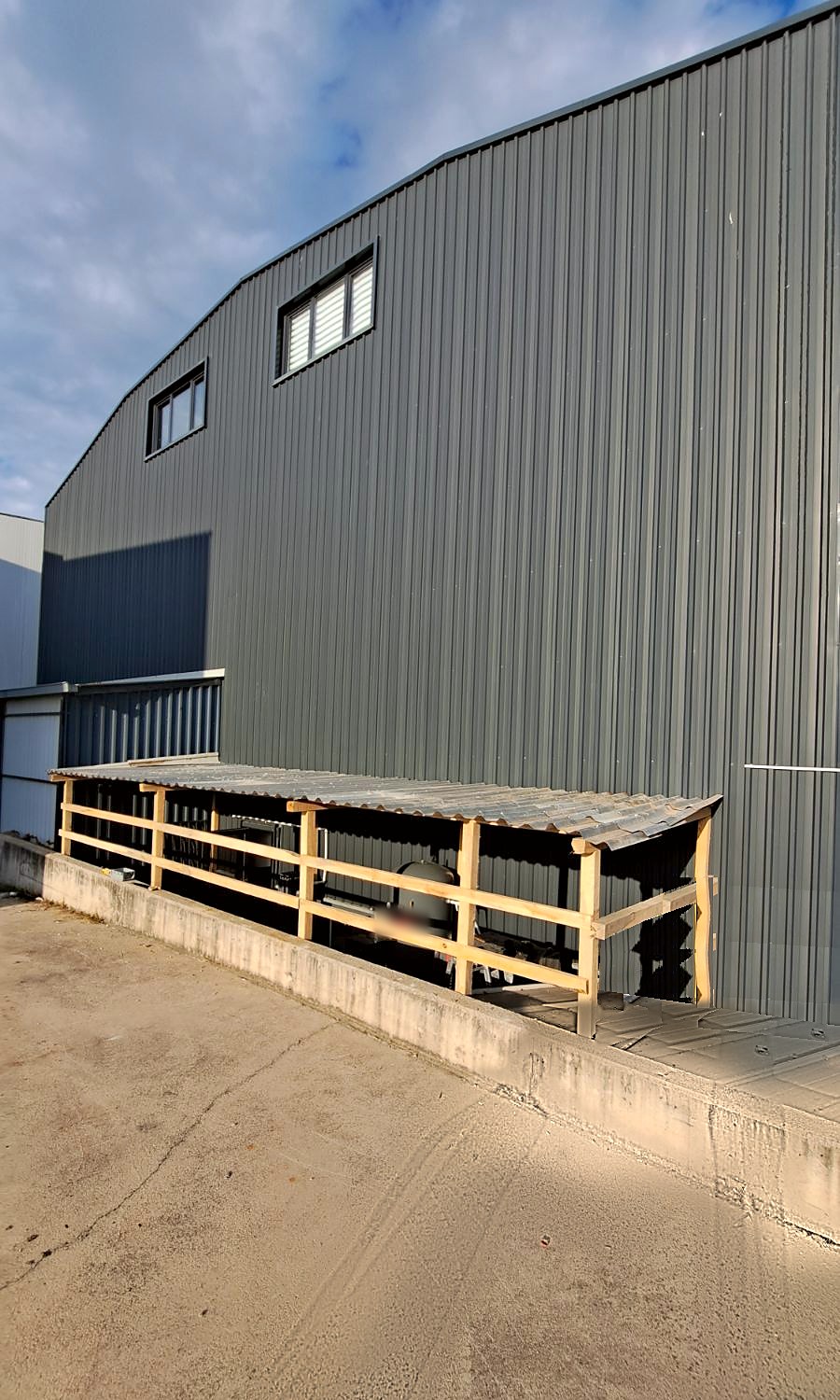 The corrugated roof of the compressor shelter seen from the side, sloping away from the building wall