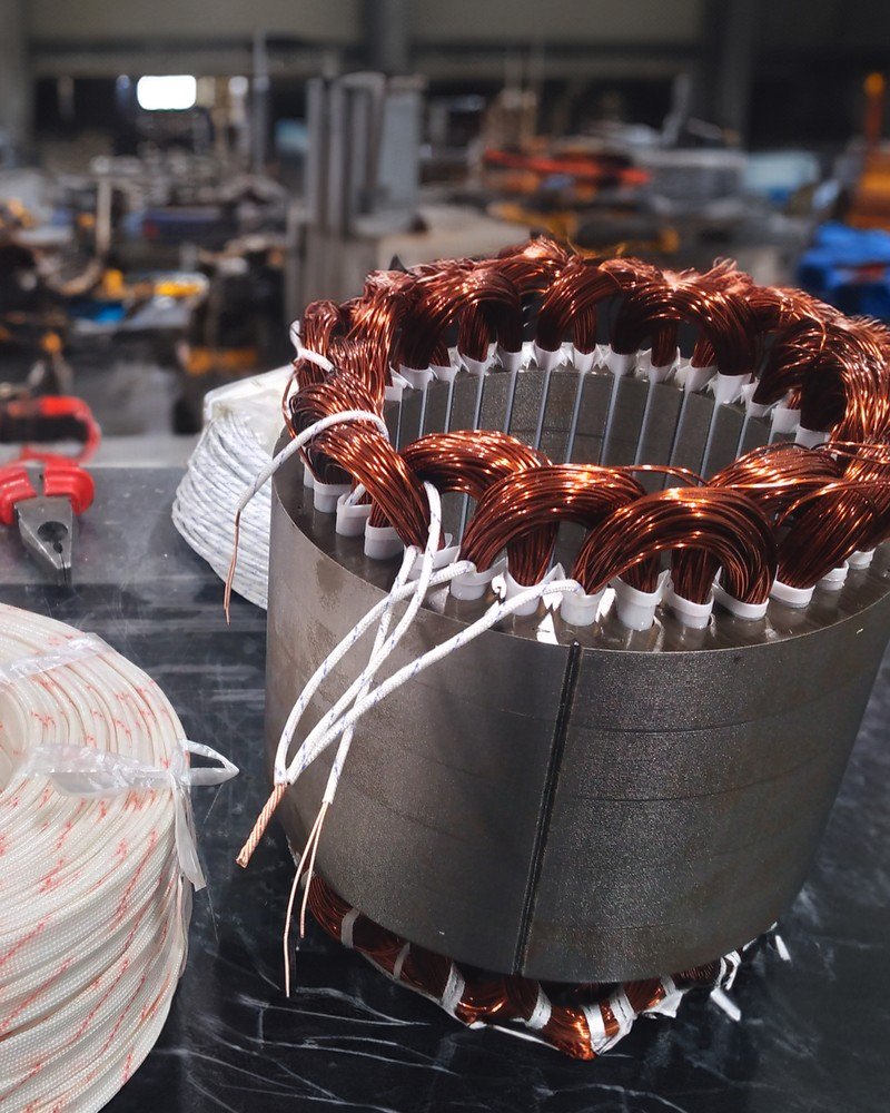 A TESUP generator stator with copper windings, next to a roll of insulated cable