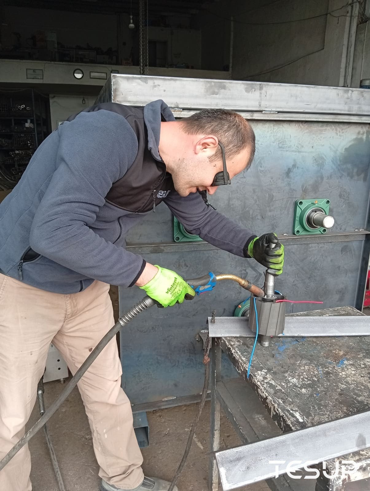 A TESUP technician welding a generator rotor and shaft at the workbench