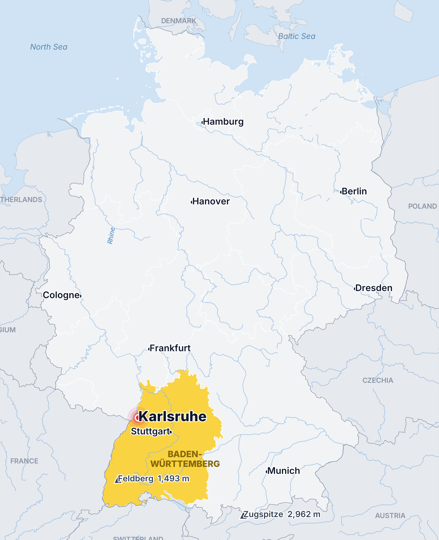 Map of Germany with its sixteen states, Baden-Württemberg highlighted in gold, Karlsruhe marked with a pin and the Feldberg and Zugspitze peaks shown