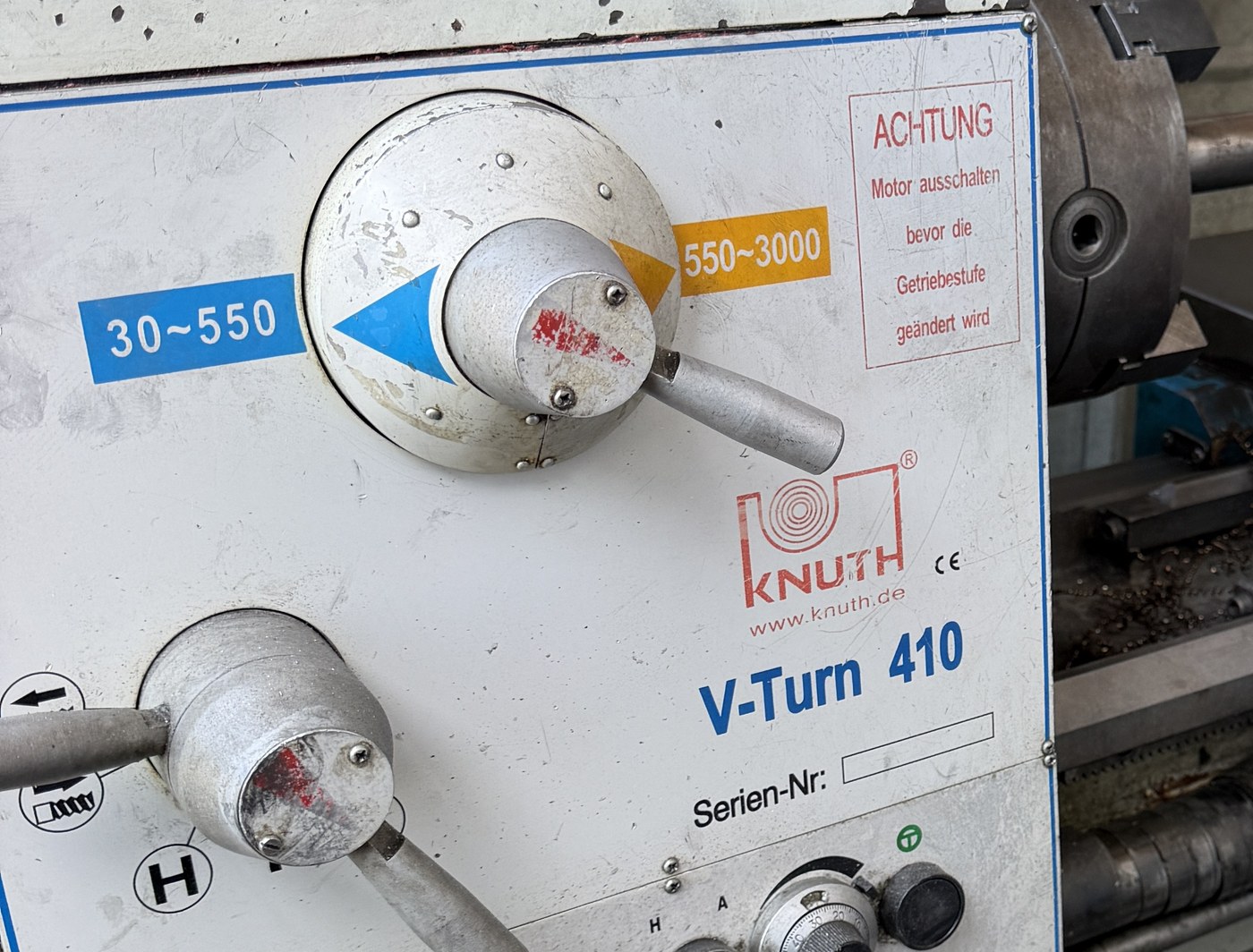 Close-up of the KNUTH V-Turn 410 front panel: a gear range lever between labels reading 30 to 550 and 550 to 3000, a red ACHTUNG plate in German, the KNUTH logo with a CE mark, the model name V-Turn 410 and an empty box beside the words Serien-Nr