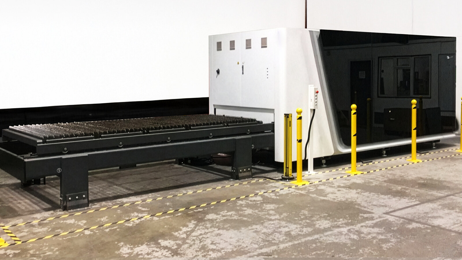 A newly installed BODOR laser cutter on a TESUP factory floor, behind yellow safety bollards and hazard tape
