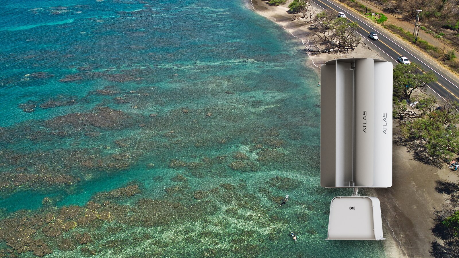 A TESUP Atlas vertical wind turbine standing above a turquoise Maui reef and a road running along the shore