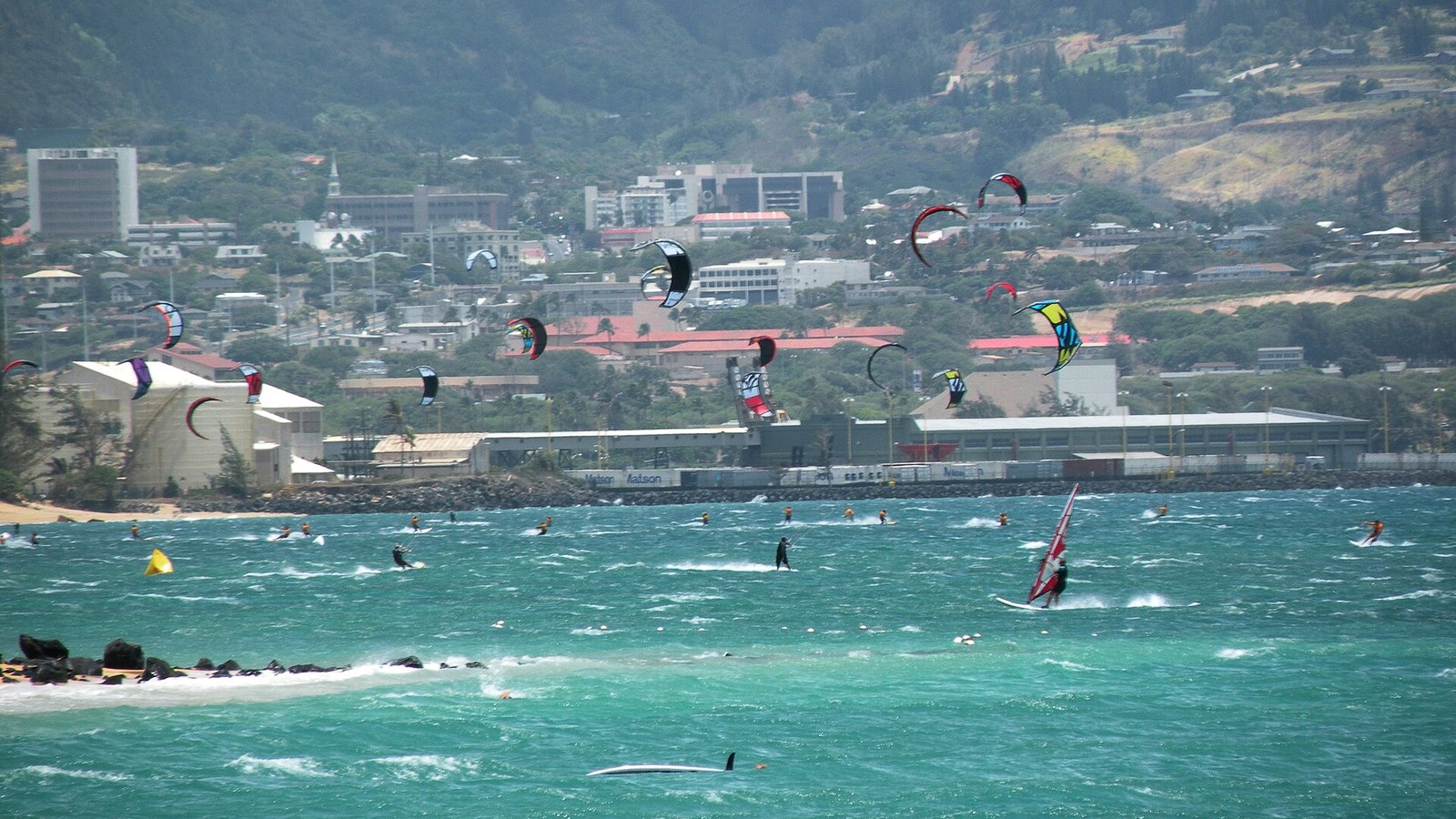 Kitesurfers and windsurfers on the turquoise water at Kanaha Beach, Kahului, with the green West Maui Mountains behind