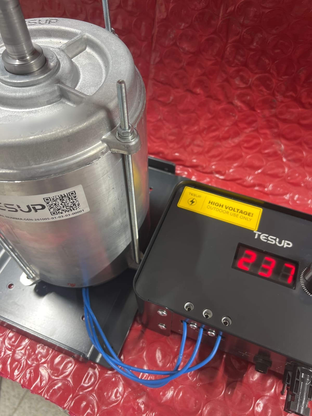 A TESUP motor/generator with its serial-number and QR-code label, wired with blue phase wires to a TESUP charge controller