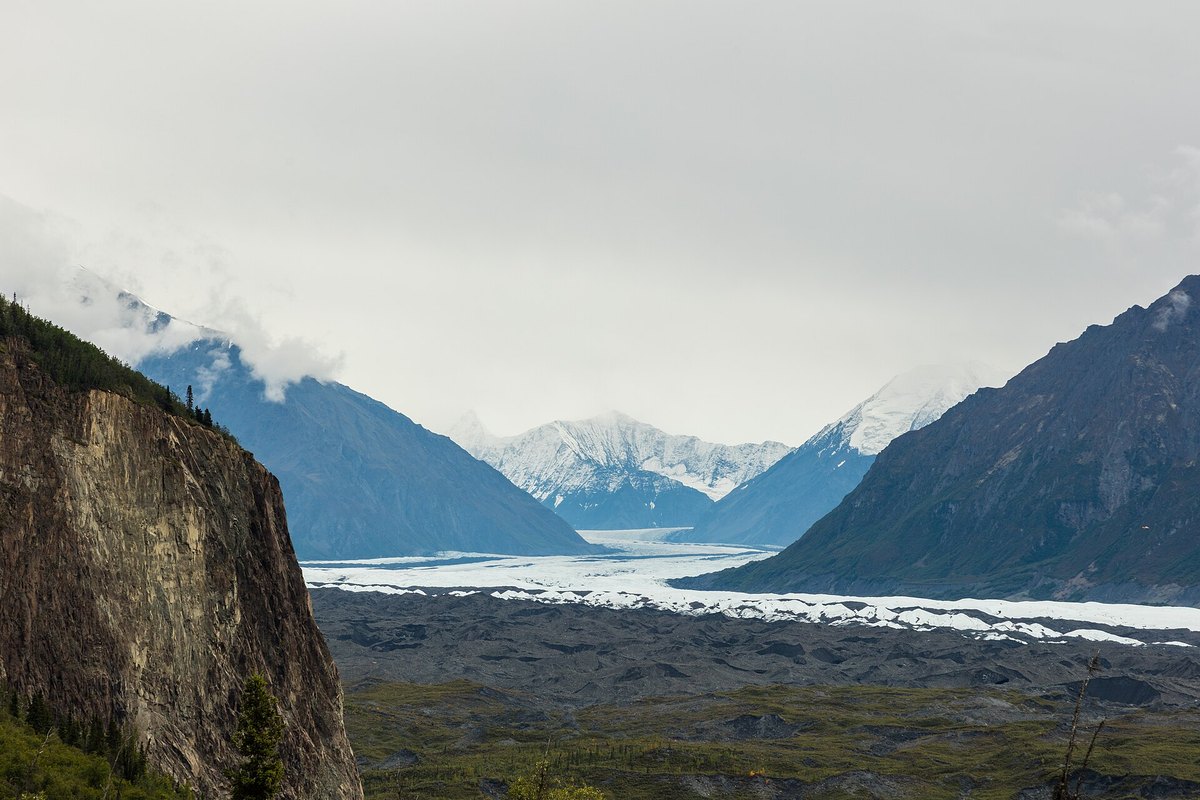 The Matanuska Glacier and its valley between steep mountains, under low cloud