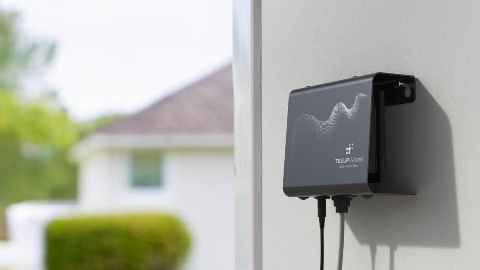 A TESUP Wizard mounted on an exterior house wall with sensor cables running from it